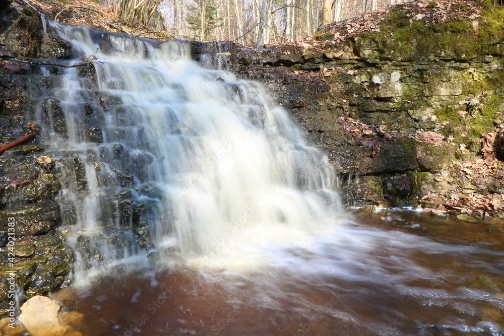 Fototapeta premium Spring, a waterfall in the forest, stones, moss. Long exposure