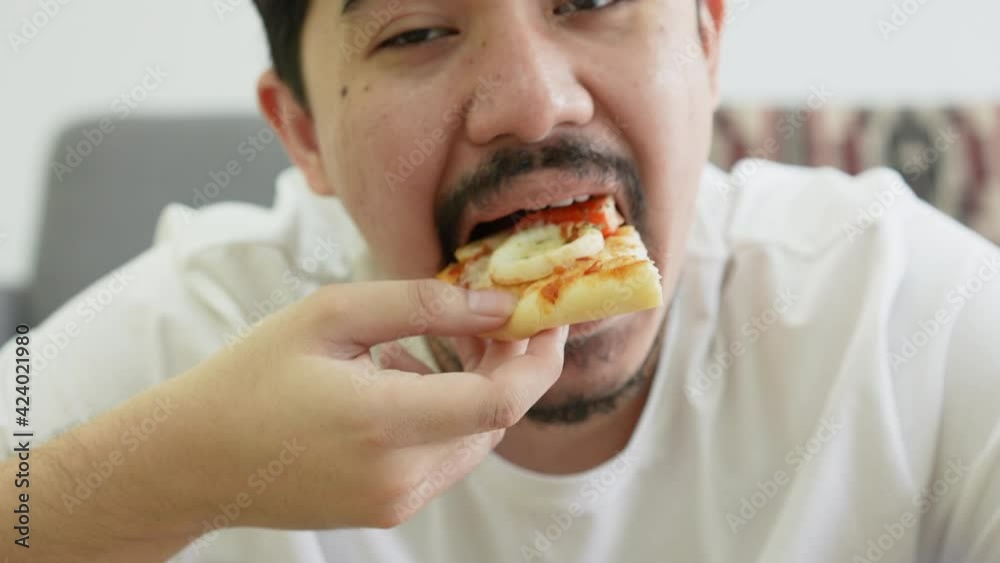 slow motion scene on middle east young man hold piece of pizza to eat with glass of cola on the table in living room for weekend lifestyle concept