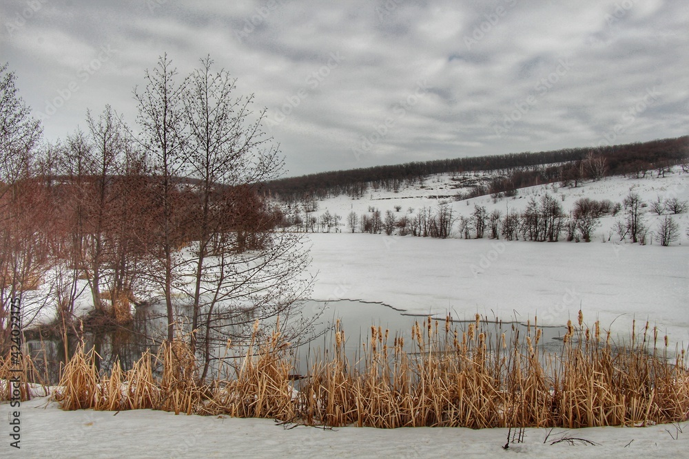 Years are melting on the lake. Spring came. Snow-covered mountains in the background. Nature comes to life after winter in a clean, ecological place Years are melting on the lake. Spring came. Snow-covered mountains in the background. Nature comes to life after winter in a clean, ecological place