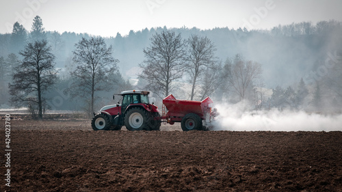 Landwirt kalkt mit dem Traktor den Acker im Frühjahr - Bodenkalk photo