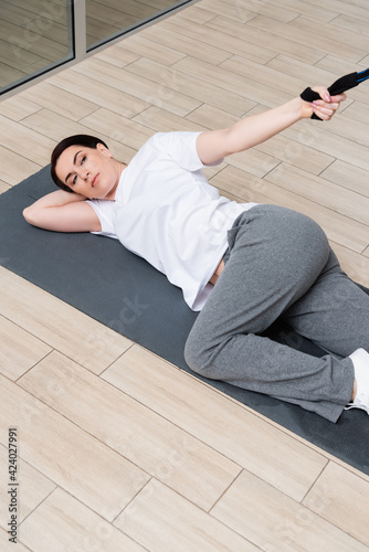 high angle view of woman lying on fitness mat while working out in rehabilitation center
