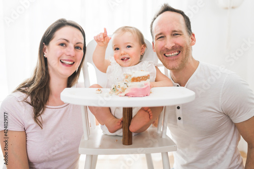 one year old little girl with daddy and mammy solemnize birthday