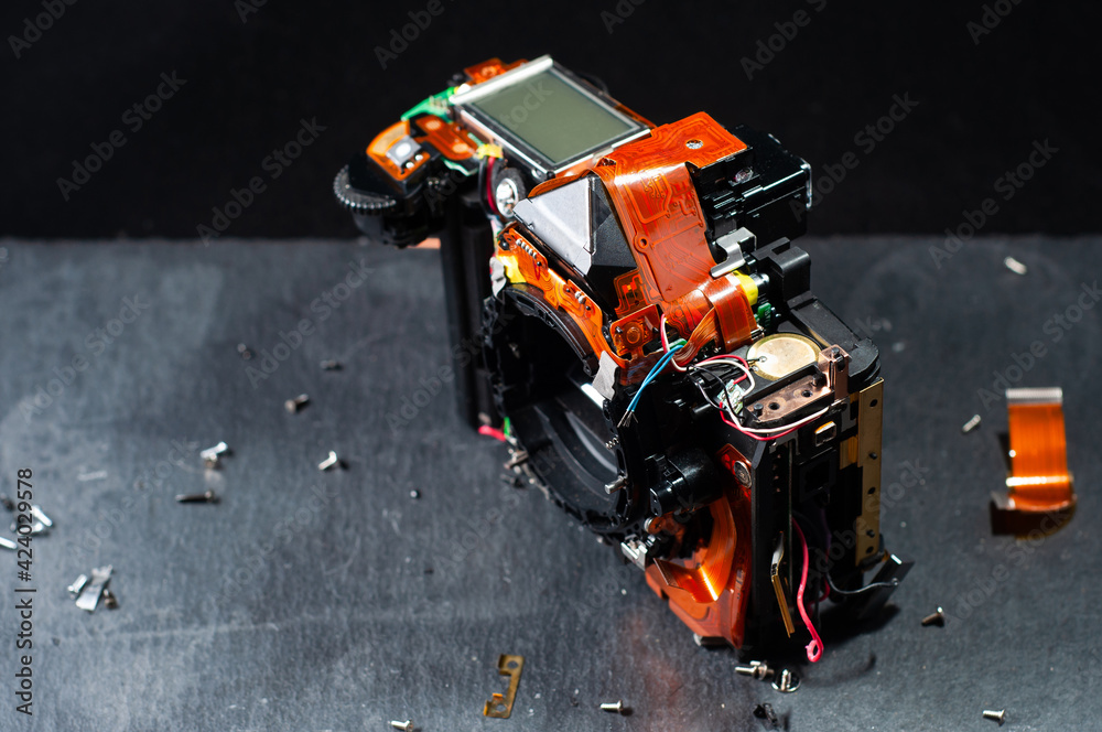 Professional repair of photographic equipment. Disassembled SLR camera on stone table on dark background
