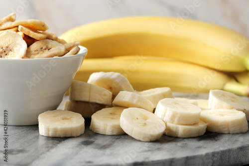 Composition with sweet dried banana slices, fresh bananas on a marble wooden  background. Dried fruit as healthy snack