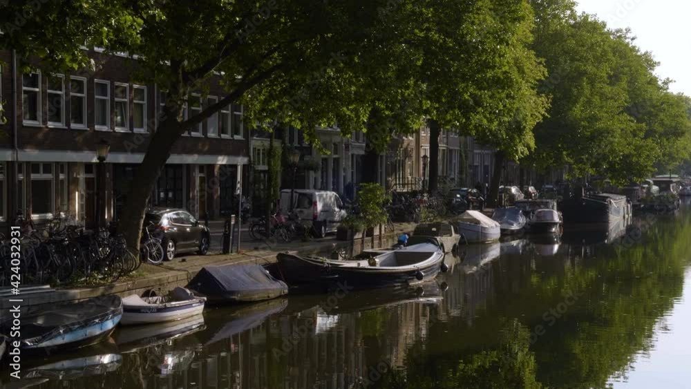 Trees reflecting in waters of quiet canal in Amsterdam Trees reflecting in waters of quiet canal in Amsterdam