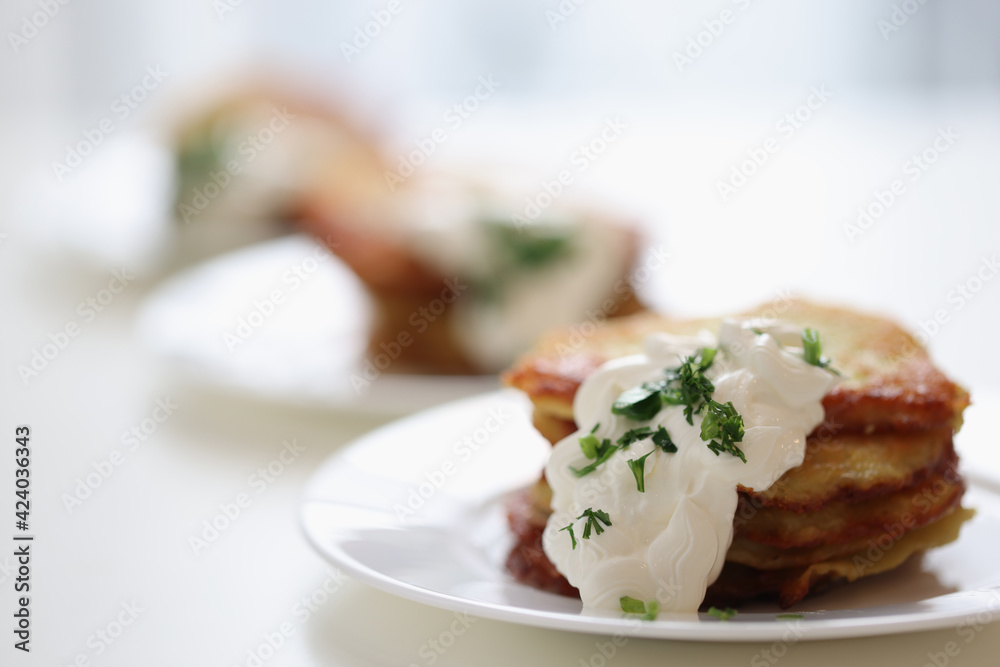 Appetizing potato pancakes with sour cream sauce and dill lying on plate