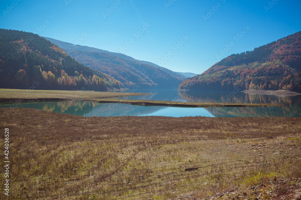 Amazing autumn landscape in the mountains with river and colorful trees on backdrop. Beautiful autumn background. Fall near Tereblia reservoir, Carpathian Mountains, Ukraine. 