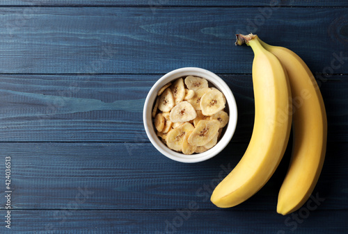 Composition with sweet dried banana slices, fresh bananas on a blue wooden  background. Dried fruit as healthy snack