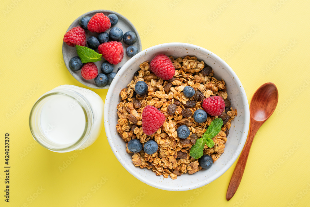 Granola with summer berries and bottle of milk on yellow background. Healthy breakfast cereals food Granola with summer berries and bottle of milk on yellow background. Healthy breakfast cereals food