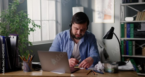 Smiling male student in headset studying online, talking to tutor via conference call on laptop. Professional call center agent sales manager having distance webcam chat on computer at home office.