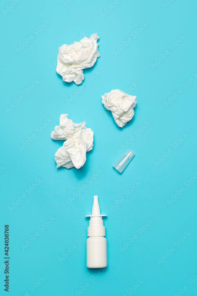 Obraz premium Nasal spray and crumpled wipes on a blue background.