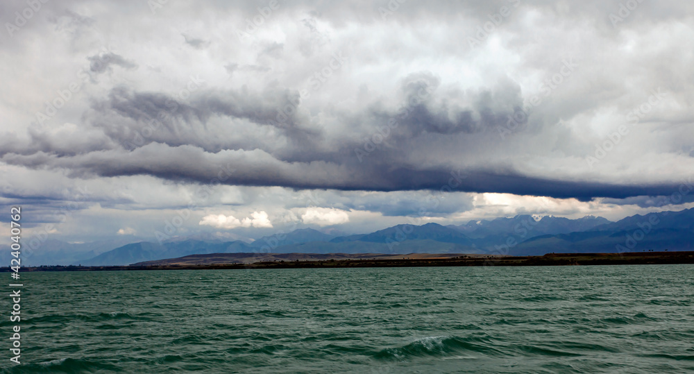 Landscape with thundercloud over the mountains and lake and the beginning of the storm.