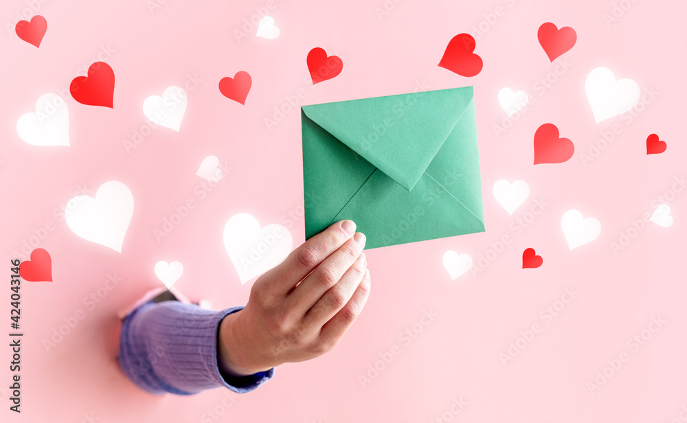 female hand hold green envelope on pink background. female hand hold green envelope on pink background.