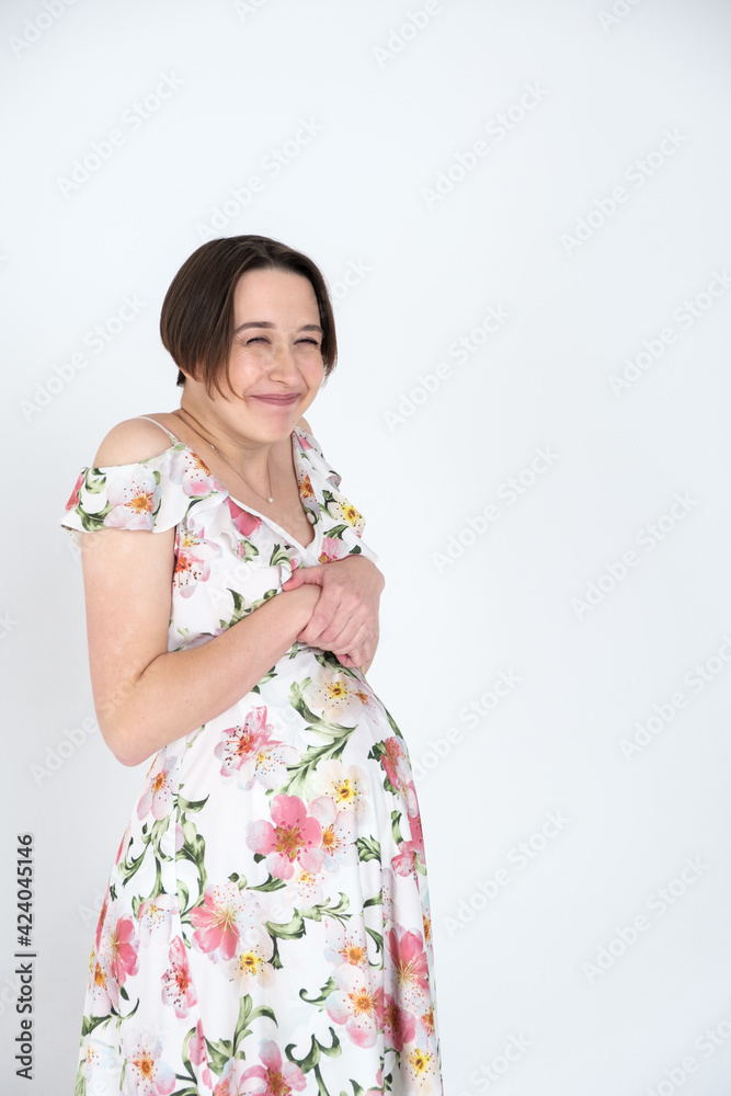 Studio portrait of cheerful young pregnant woman in summer dress on white gray background, happy pregnancy concept Studio portrait of cheerful young pregnant woman in summer dress on white gray background, happy pregnancy concept