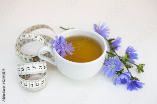 Cup with herbal tea and measuring tape on a white background. Weight loss concept.