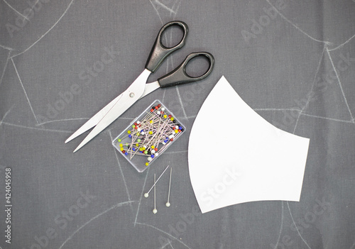 Sewing background. Sewing accessories and face mask pattern on black fabric.