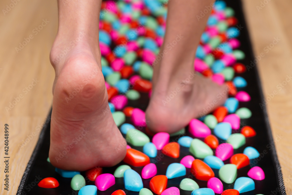 Massage mat with stones for the foot. Leg close-up with pressure points from stones.