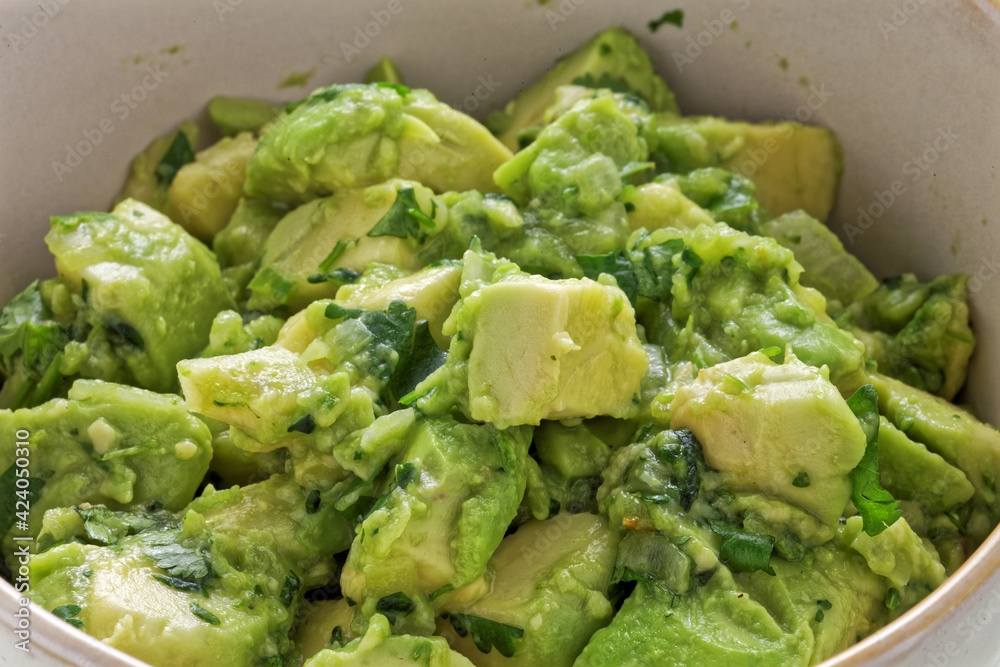 Close-up view of chunky guacamole in ceramic bowl. Mexican cuisine. Close-up view of chunky guacamole in ceramic bowl. Mexican cuisine.