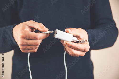 Close up of hand inserting a USB cable charger into portable power bank. Media. Close up of mans hand inserting a cable into charger.