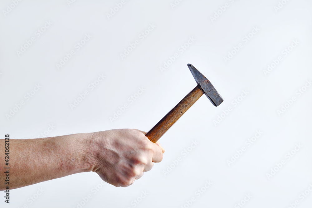 Old hammer in a man's hand on a light background Old hammer in a man's hand on a light background
