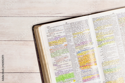 Canvas Print Used and Highlighted Bible Open on a White Wood Table