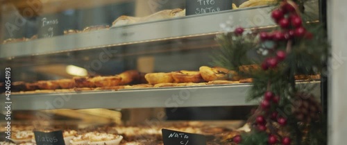 Cafe shop window display in Lisbon, Portugal during a winter holiday season. Traditional Portuguese egg tart pastry. Slow motion.