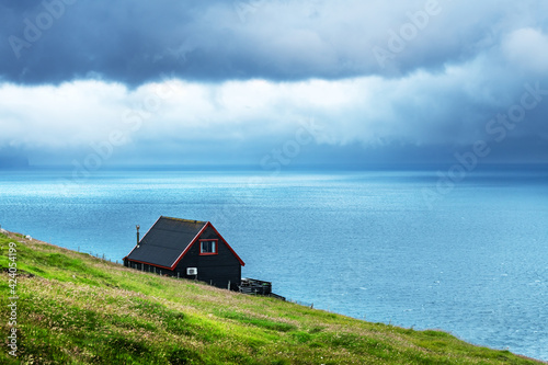 Black house on famous faroese Witches Finger Trail and Koltur island on background. Sandavagur village, Vagar island, Faroe islands, Denmark. Landscape photography © Ivan Kmit