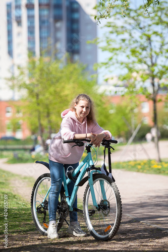 Girl on a mountain bike on urban street, beautiful portrait of a cyclist in sunny weather