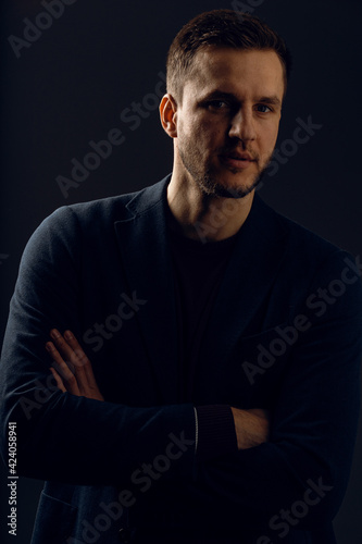 Confident professional fashion male posing in studio. Business man portrait on dark background. Handsome young man weared suit.