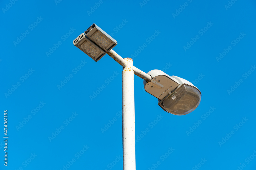 Street lamp on a lamppost against the blue sky, city illumination Street lamp on a lamppost against the blue sky, city illumination