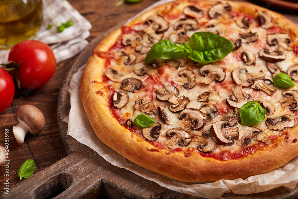 Pizza with mushrooms. American style homemade pizza with champignon mushrooms, mozzarella cheese and tomato sauce. Freshly baked and served with basil leafs. Vegetarian dish