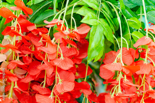 Artificial red flowers with green leaves.