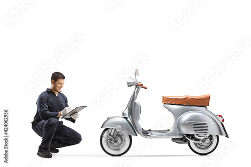 Motorbike mechanic kneeling and checking a vintage model scooter