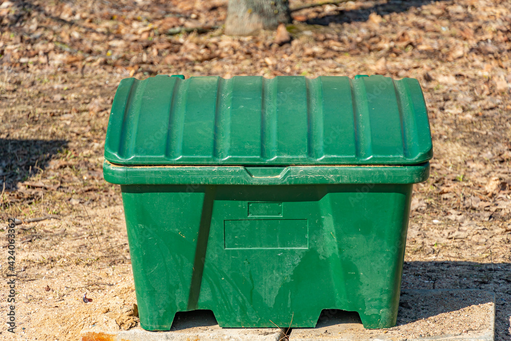Green container for sand to sprinkle on the sidewalk during frost Green container for sand to sprinkle on the sidewalk during frost