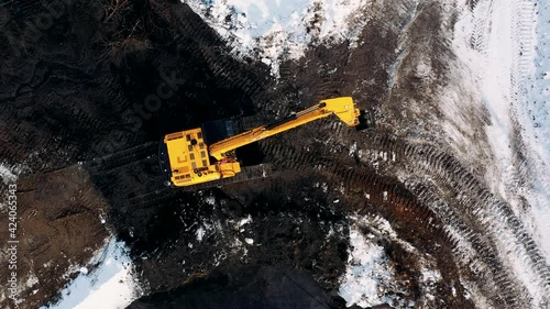 Aerial top down view of yellow hydraulic excavator working in quarries site. Construction digger machine. Heavy equipment for digging in the ground. Top view from drone. Industrial style.