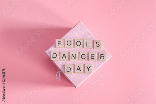 Fools day gift...Gift box with a fool's day from wooden cubes lie in the middle on a pink background, top view close-up. photo