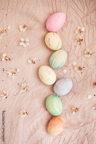 Beautiful watercolor paints on Easter eggs that lie on a delicate pink fabric along with blooming cherry. Easter concept.