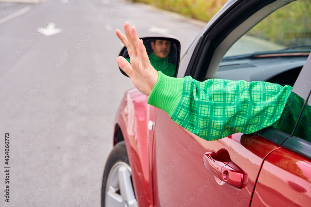 Rear view of a driver's arm waving to someone from a moving car. Rear view of a driver's arm waving to someone from a moving car.