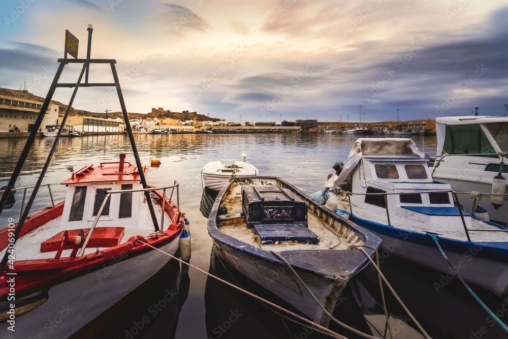 Fototapeta premium fishing boats in the fishing port of Almeria with the Alcazaba in the background overlooking the city at sunrise