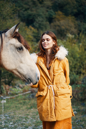 woman in nature in a jacket near a donkey friendship animals