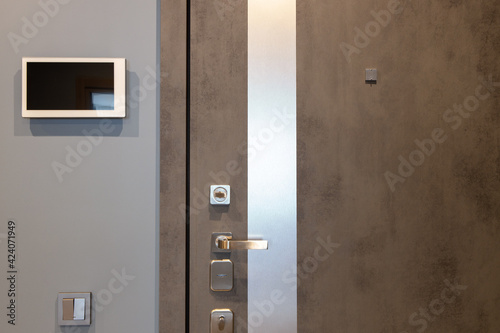 Shabby design entrance door in a modern apartment hallway, video intercom device on the wall. Neutral tones. Security concept, trendy interior. Horizontal