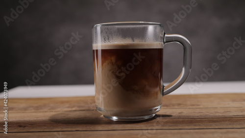 Pour milk into a freshly brewed cup of coffee - studio photography