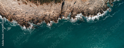 Aerial view of rocky beach and sea with clear blue water at sunset. Coast of the Adriatic Sea at sunset in summer. View from above. Landscape with clear azure water, stones and rocks