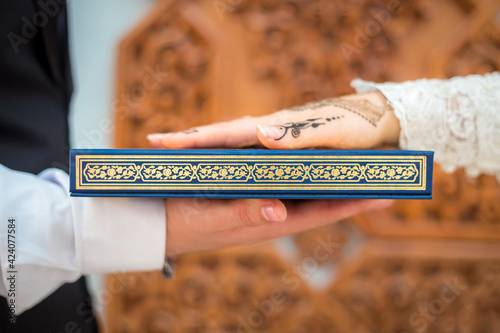 Muslim wedding ceremony bride and groom holding together a Quran take an oath of allegiance.
 photo