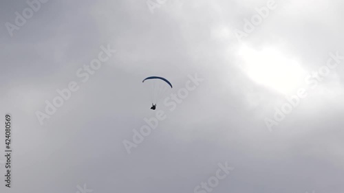 Paraglider, acropilot. Aerobatics. Acreage. A helicopter. Blue wing. Gray sky. photo