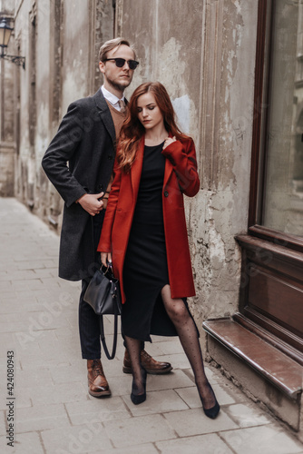 Woman in black dress and wine color coat, man in classic business suit with sweater