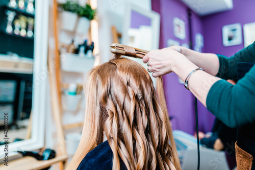 Beautiful hairstyle of young blond woman after dyeing hair in hair salon.