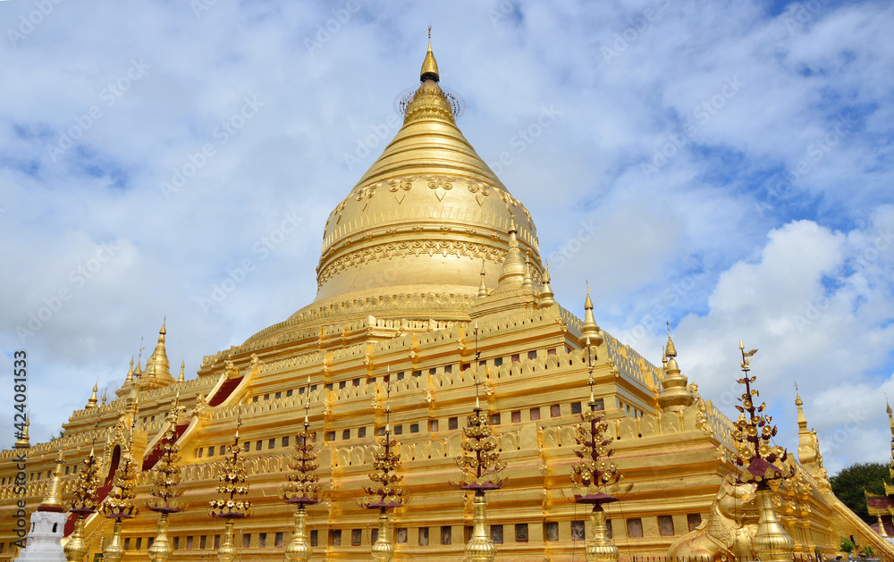Shwezigon Pagoda, the golden temple in Bagan shines brilliantly under sunlight and in background of cloudy sky