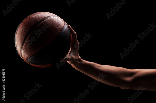 Professional basketball player holding a ball against black background © Nikola Spasenoski