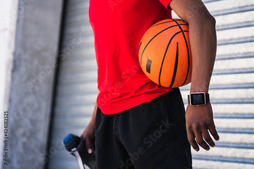 Afro athlete man holding a basketball ball outdoors.